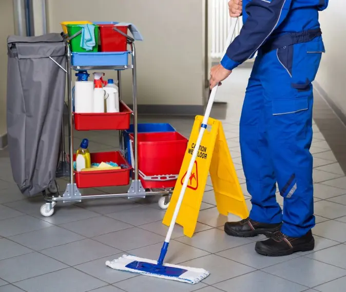 A man cleaning a floor with a mop and cleaning supplies.